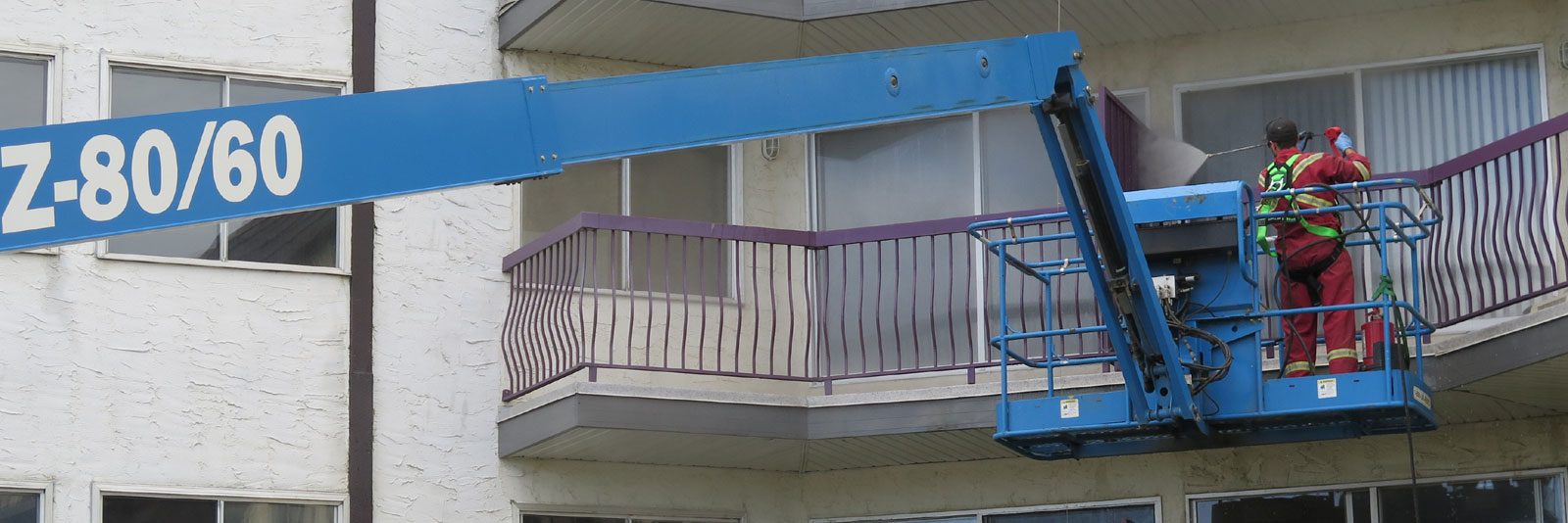 employee on lift pressure cleaning the exterior of a building